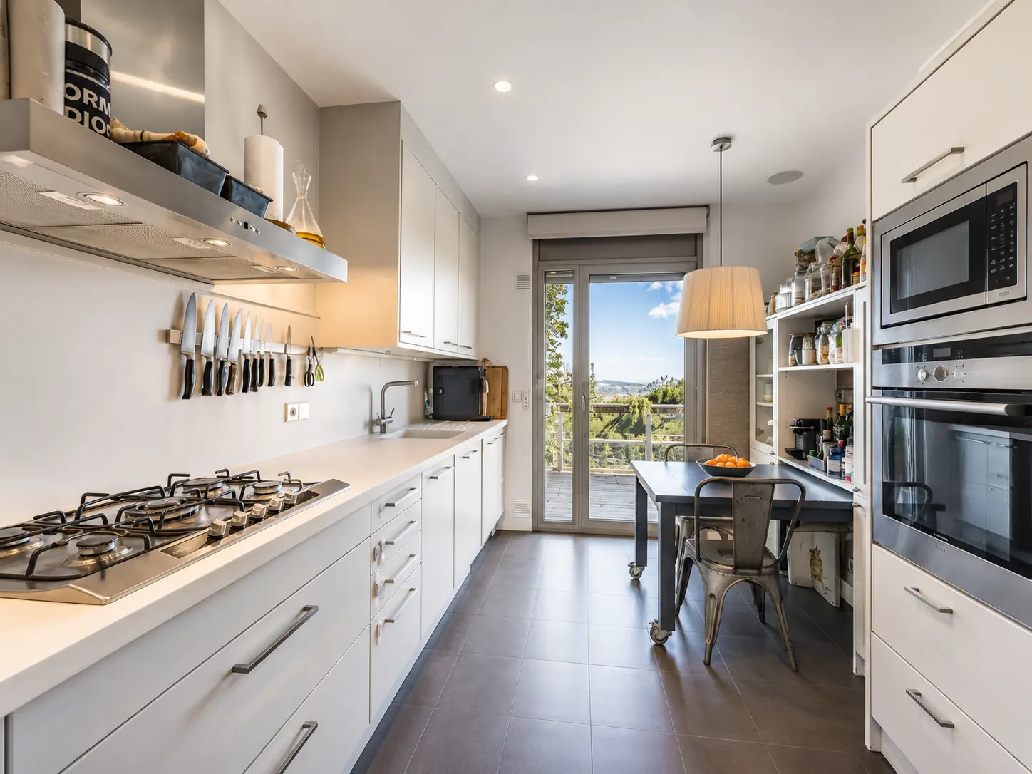 Modern white kitchen with terrace access and hillside views