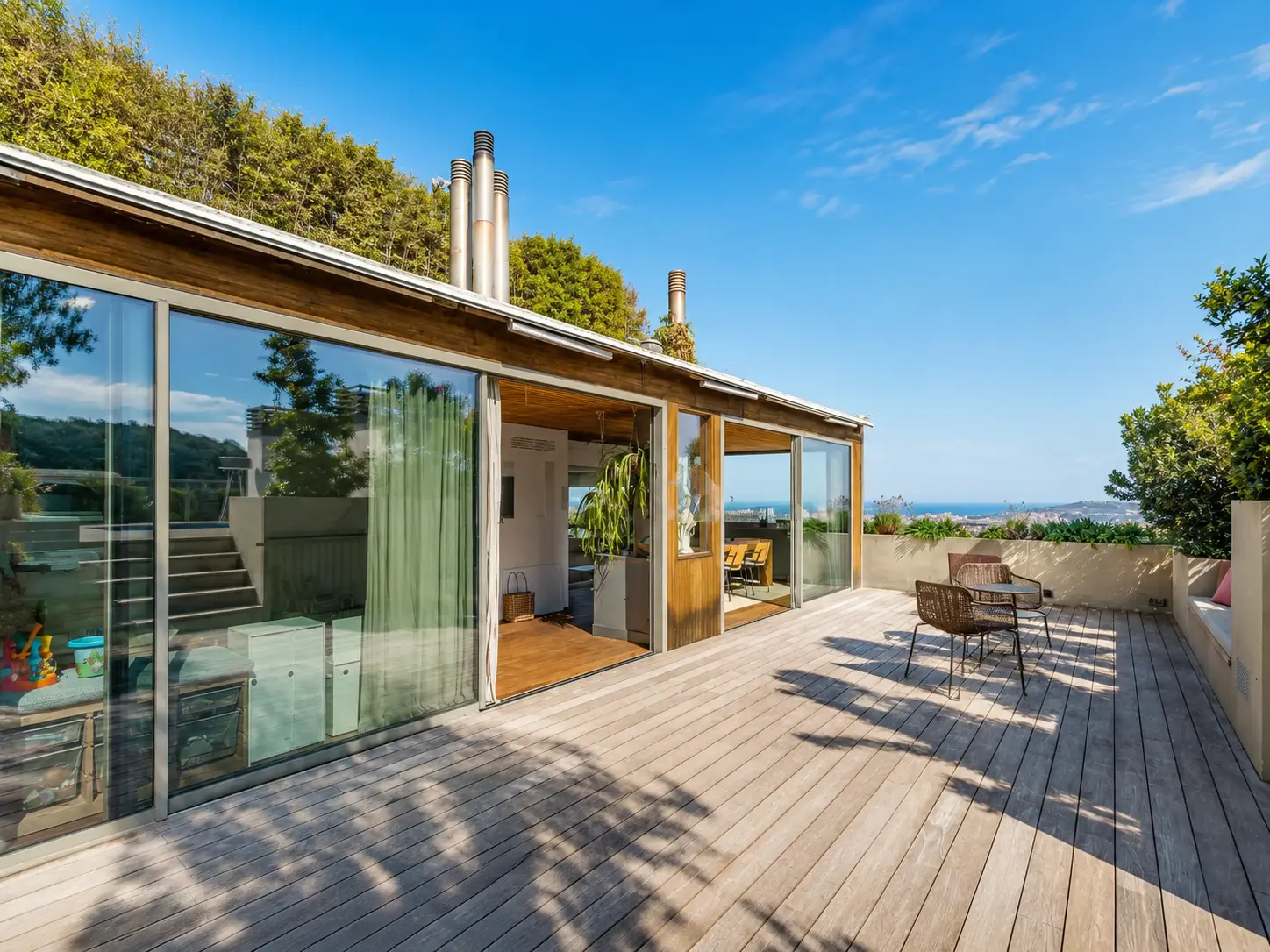 Wide wooden deck terrace with glass sliding doors and city views
